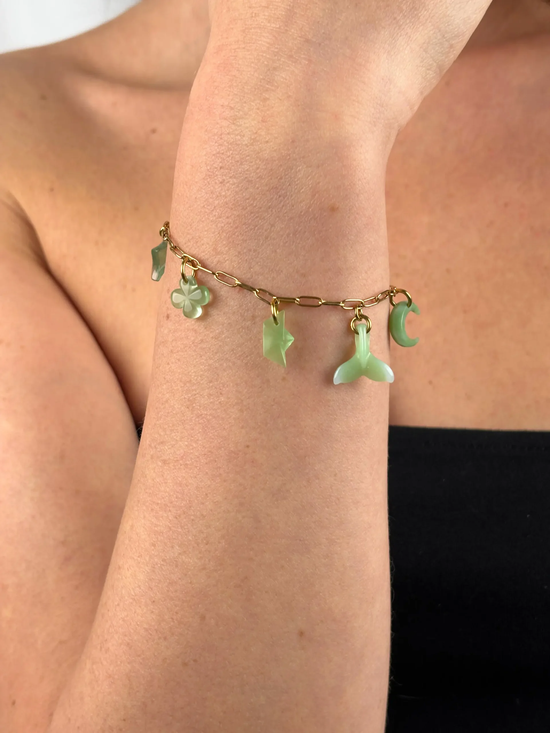 Bracelet doré porté avec cinq charms verts