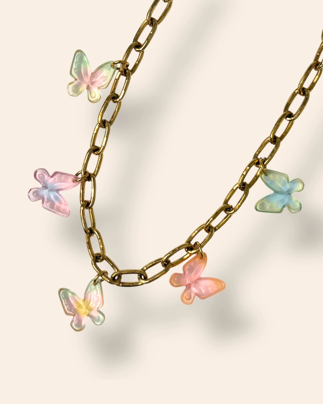 Collier cinq papillon aux couleurs dégradées sur fond beige