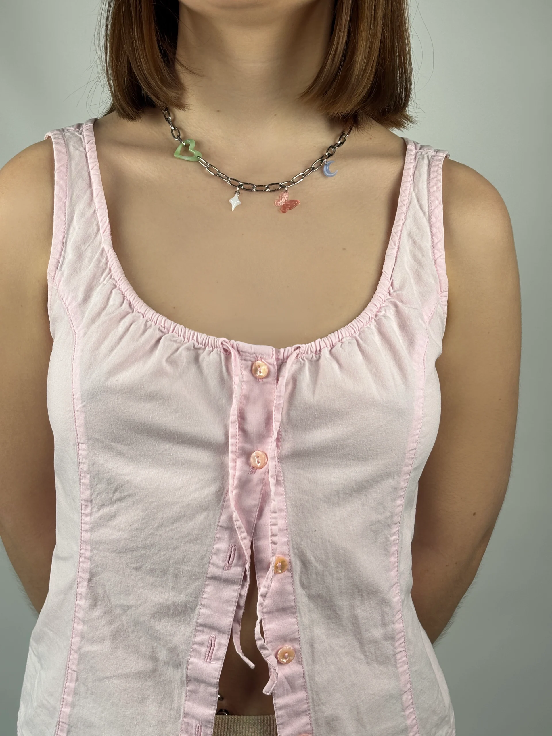 Collier gros maillon argenté avec quatre charms. Une coeur vert ajouré, une étoile blanche, un papillon rose et une lune bleue claire.