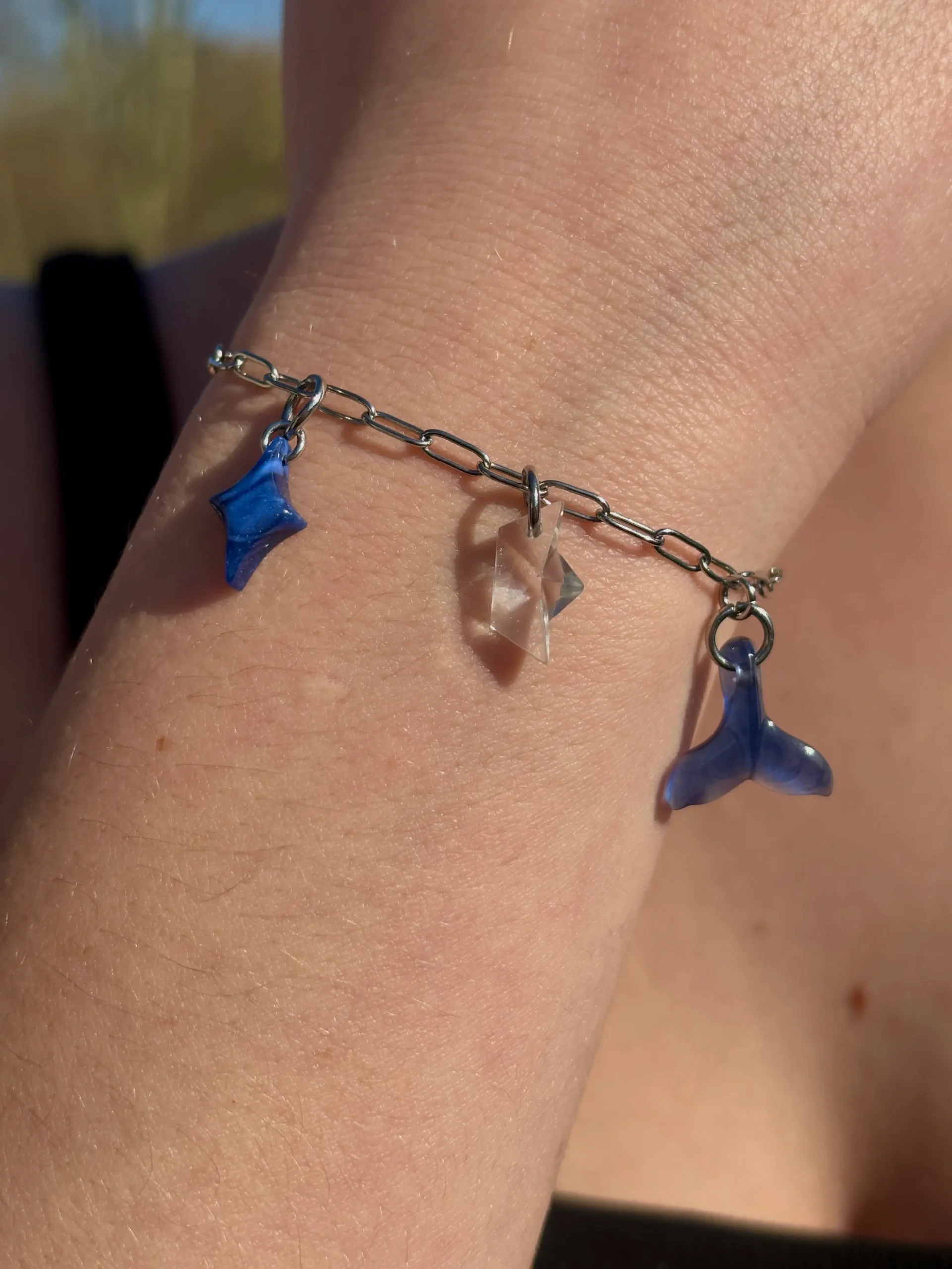 Bracelet maillons moyens trois charms. Une étoile bleue, un bateau transparent une queue de baleine bleue