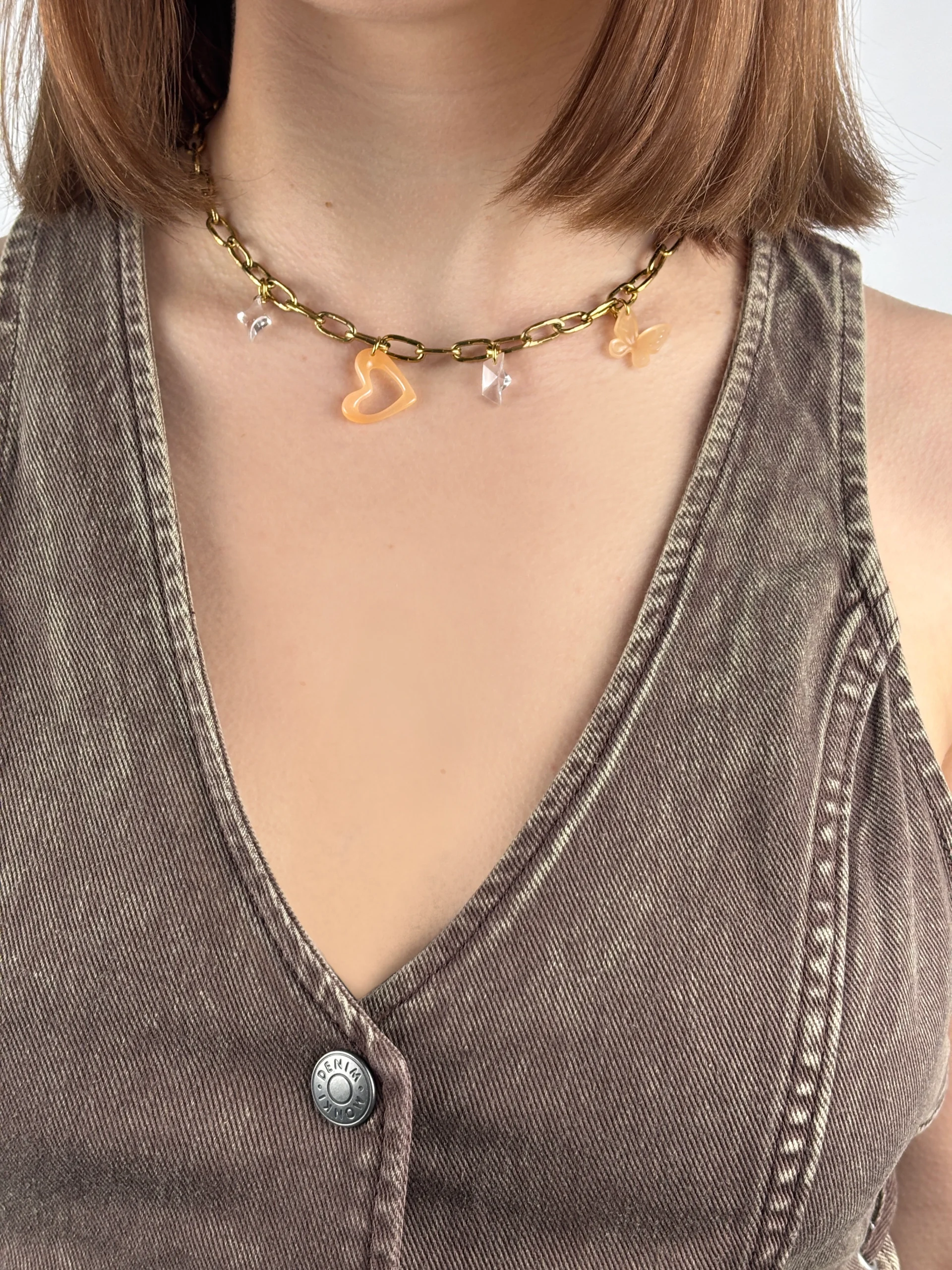 Collier gros maillon doré avec quatre charms. Une étoile transparente, un coeur ajouré pêche, bateau transparent, papillon pêche