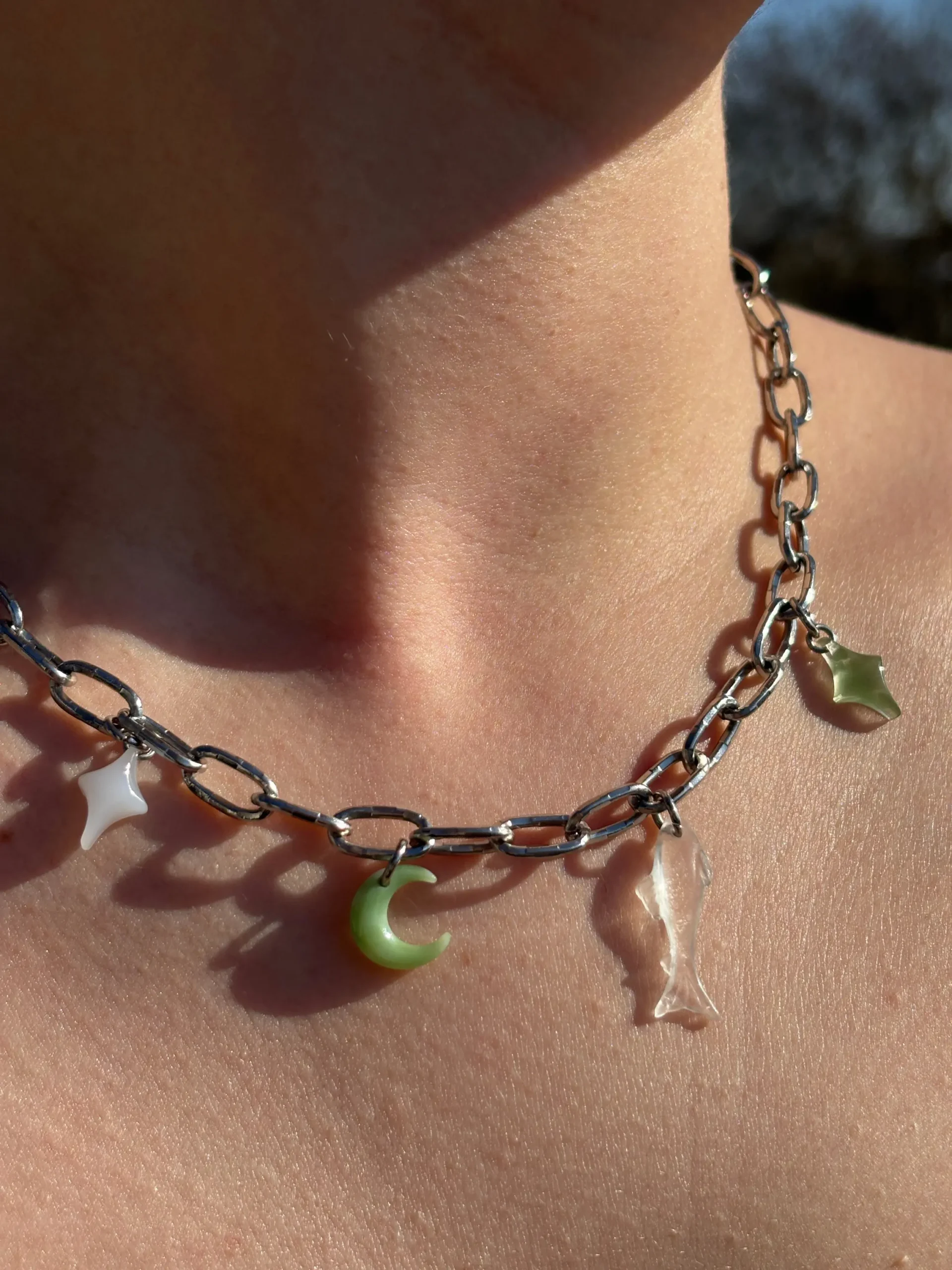 Collier argenté gros maillons quatre charms. Une étoile blanche, une lune verte, un poisson transparent’ une étoile verte