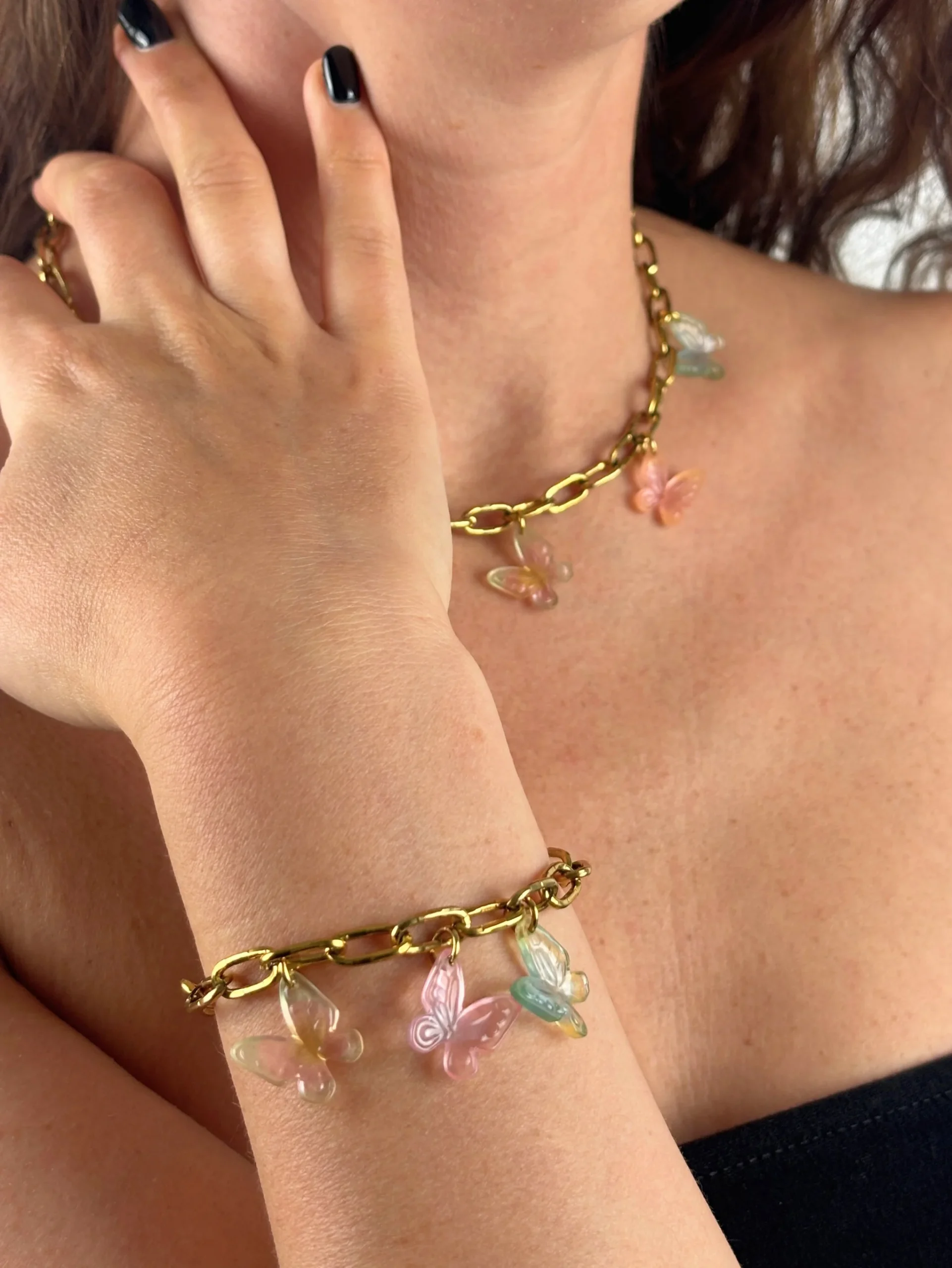 Fille portant un collier et un bracelet doré orné de Charms papillon aux couleurs dégradées