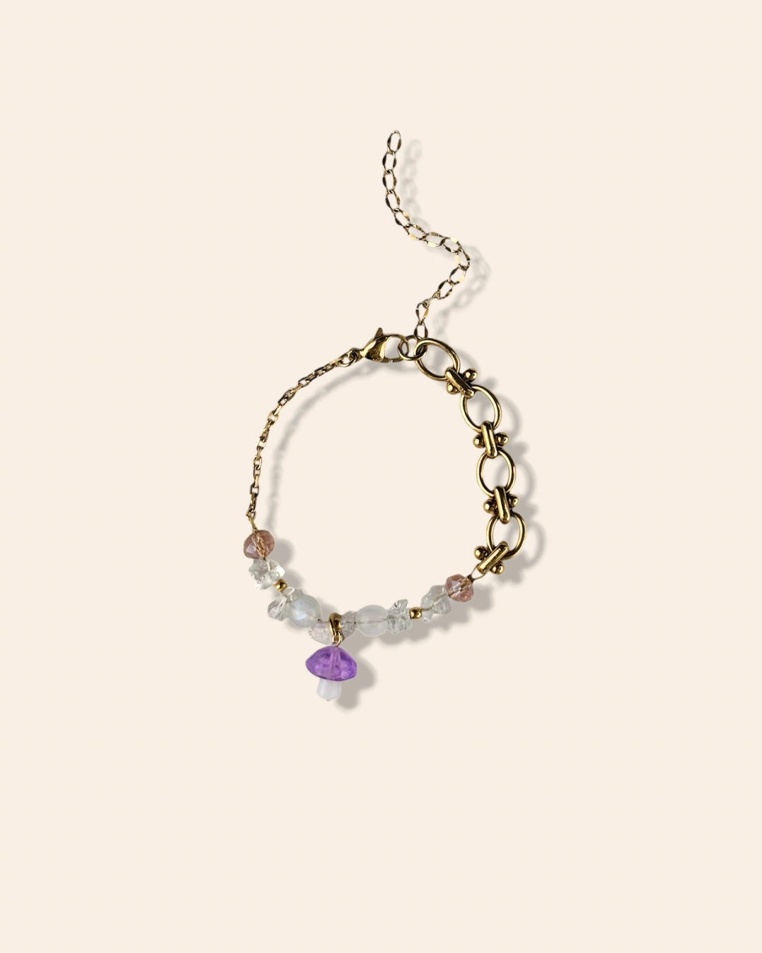 Bracelet tendance et asymétrique en perle de verre orné d'un charm champignon violet.