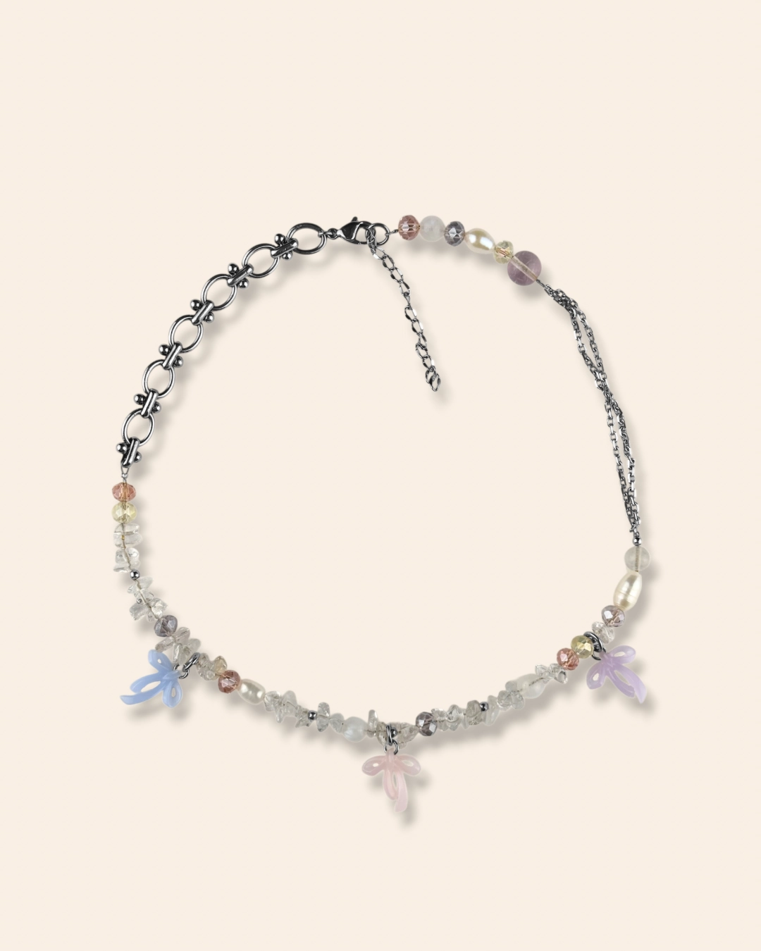 Collier asymétrique, tendance et girly aux couleurs pastels. Mélange de perles, pierres naturelles et chaine en acier inoxydable. Orné de trois noeuds faits main.
