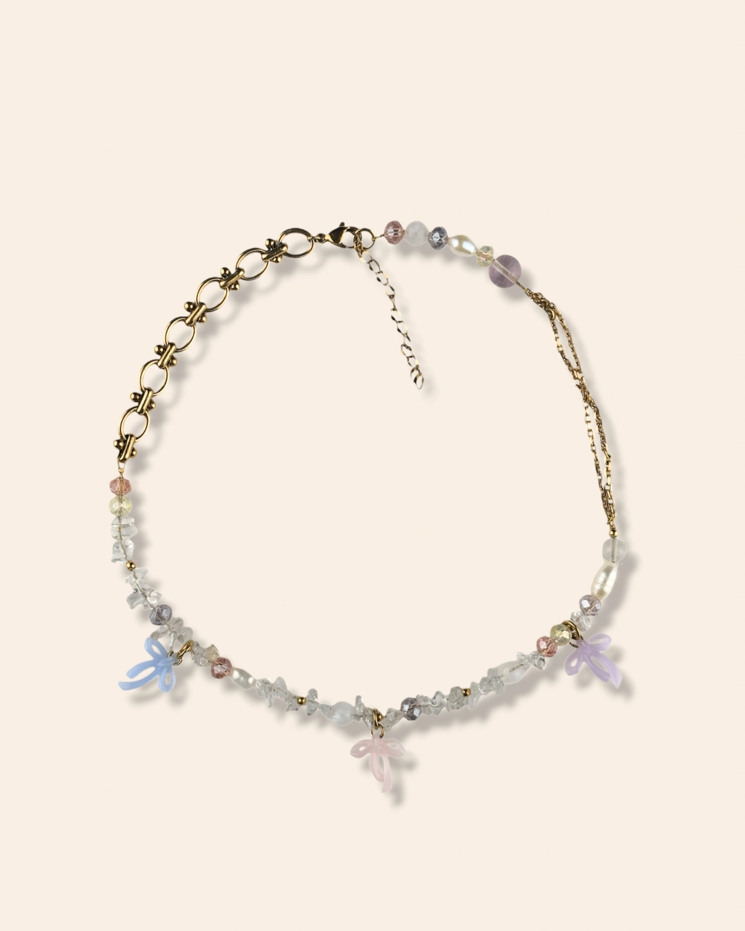 Collier asymétrique, tendance et girly aux couleurs pastels. Mélange de perles, pierres naturelles et chaine en acier inoxydable. Orné de trois noeuds faits main.