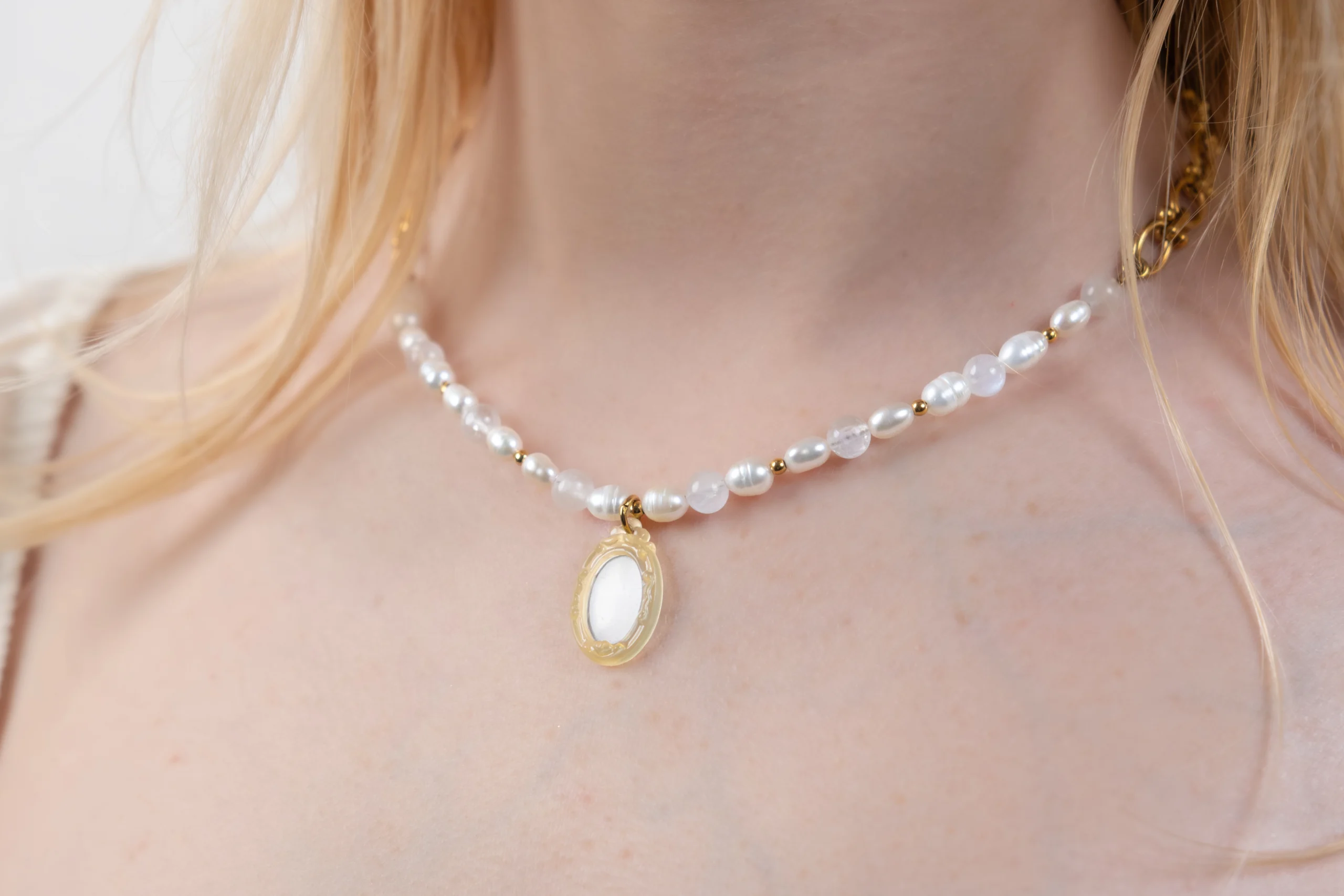 Collier associant perles d'eau douces, pierres de lune et acier inoxydable. Collier orné d'un pendentif charm miroir jaune.
