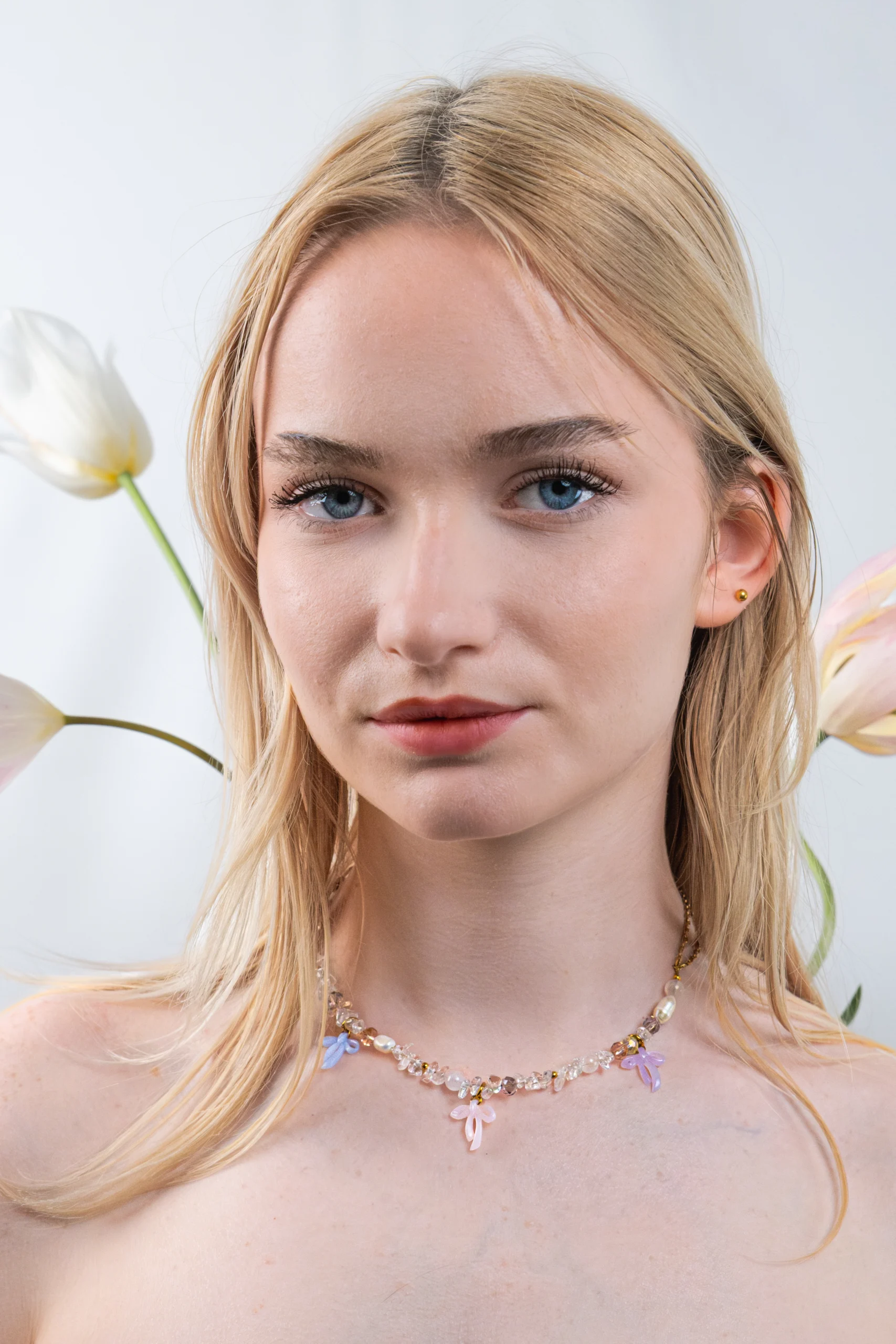 Collier asymétrique, tendance et girly aux couleurs pastels. Mélange de perles, pierres naturelles et chaine en acier inoxydable. Orné de trois noeuds faits main.
