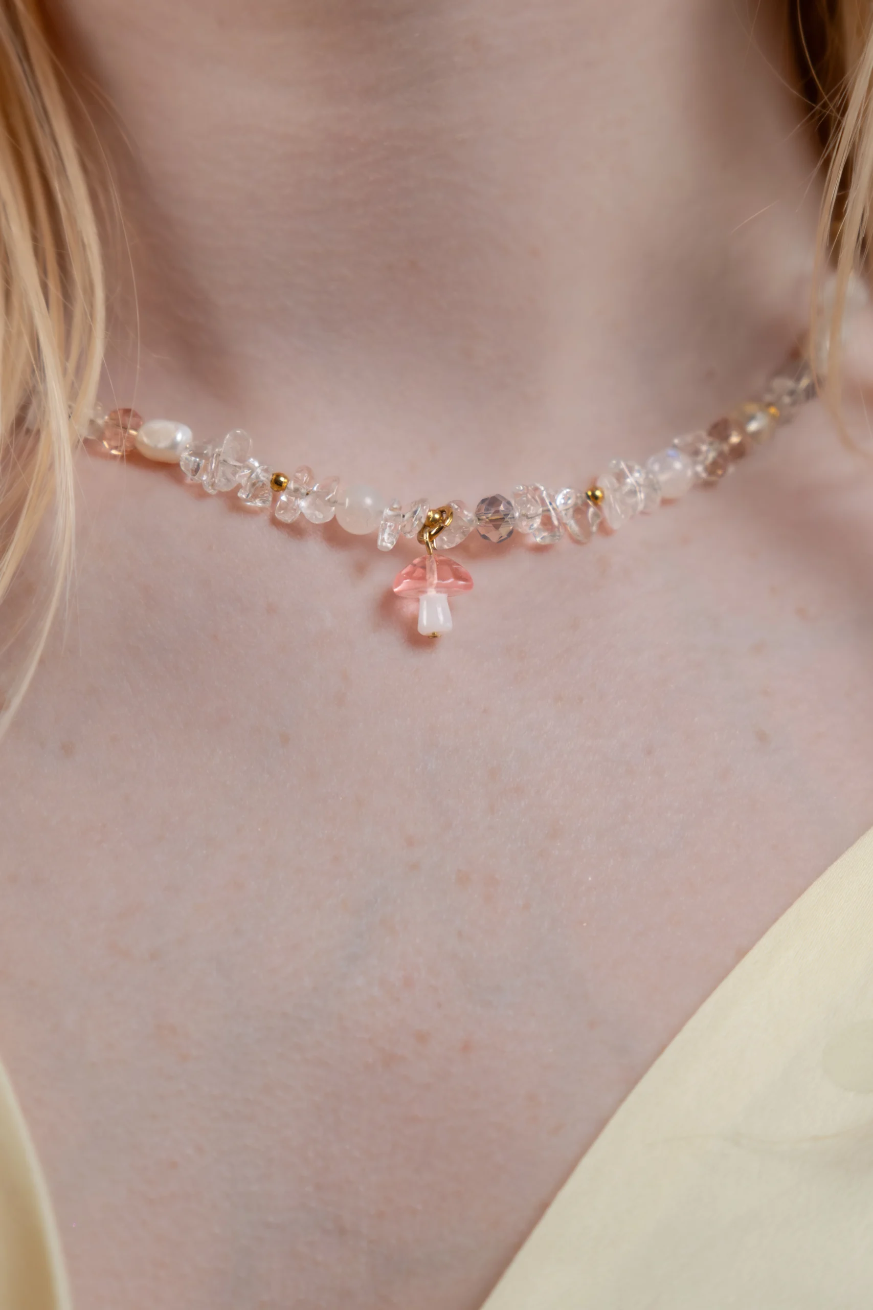 Collier tendance et asymétrique en perle de verre orné d'un charm champignon rose.