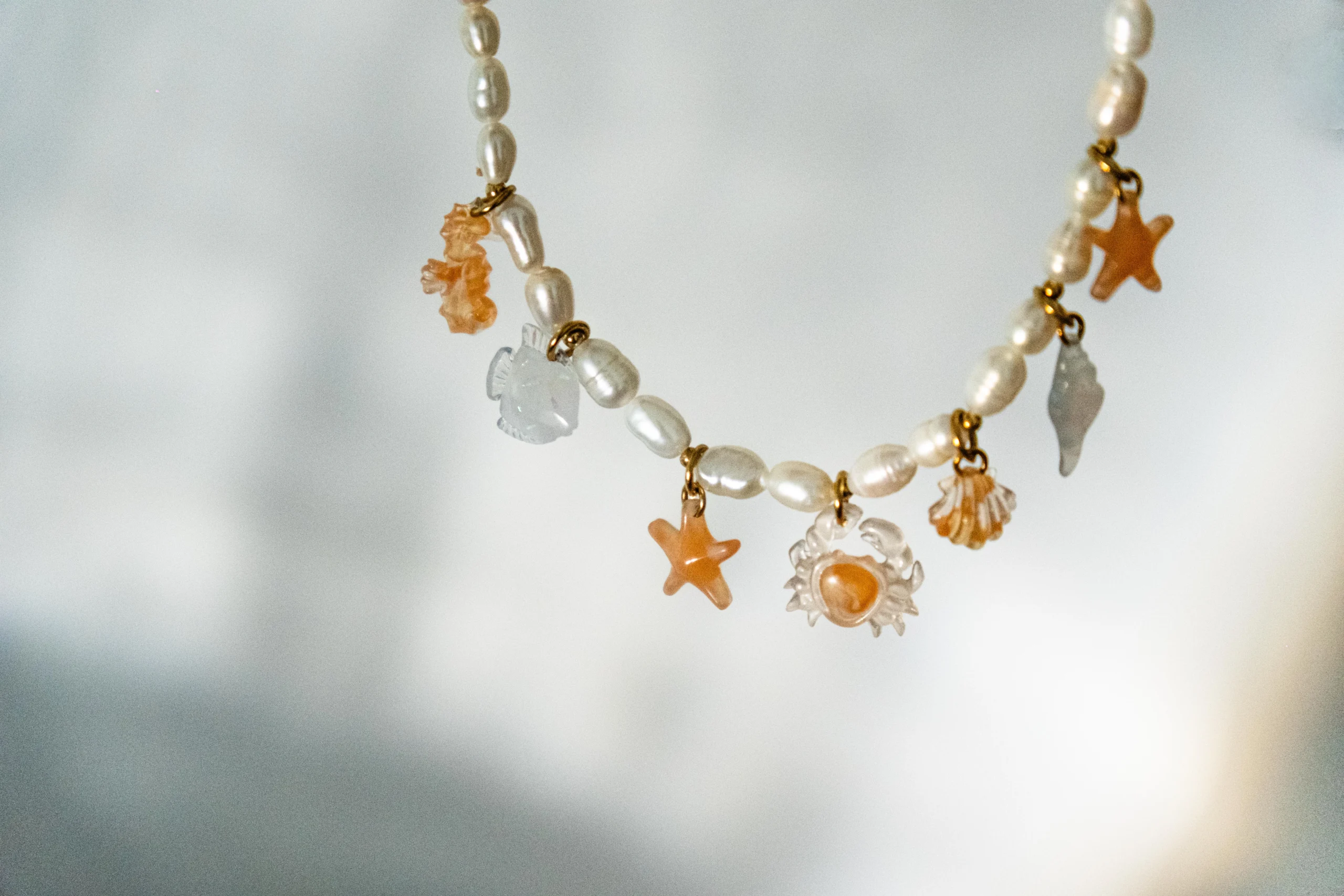 Collier Sunset en perles avec charms marins hippocampe, étoiles de mer, crabe et coquillages aux tons corail, collection Mermaid Odyssée Bijoux