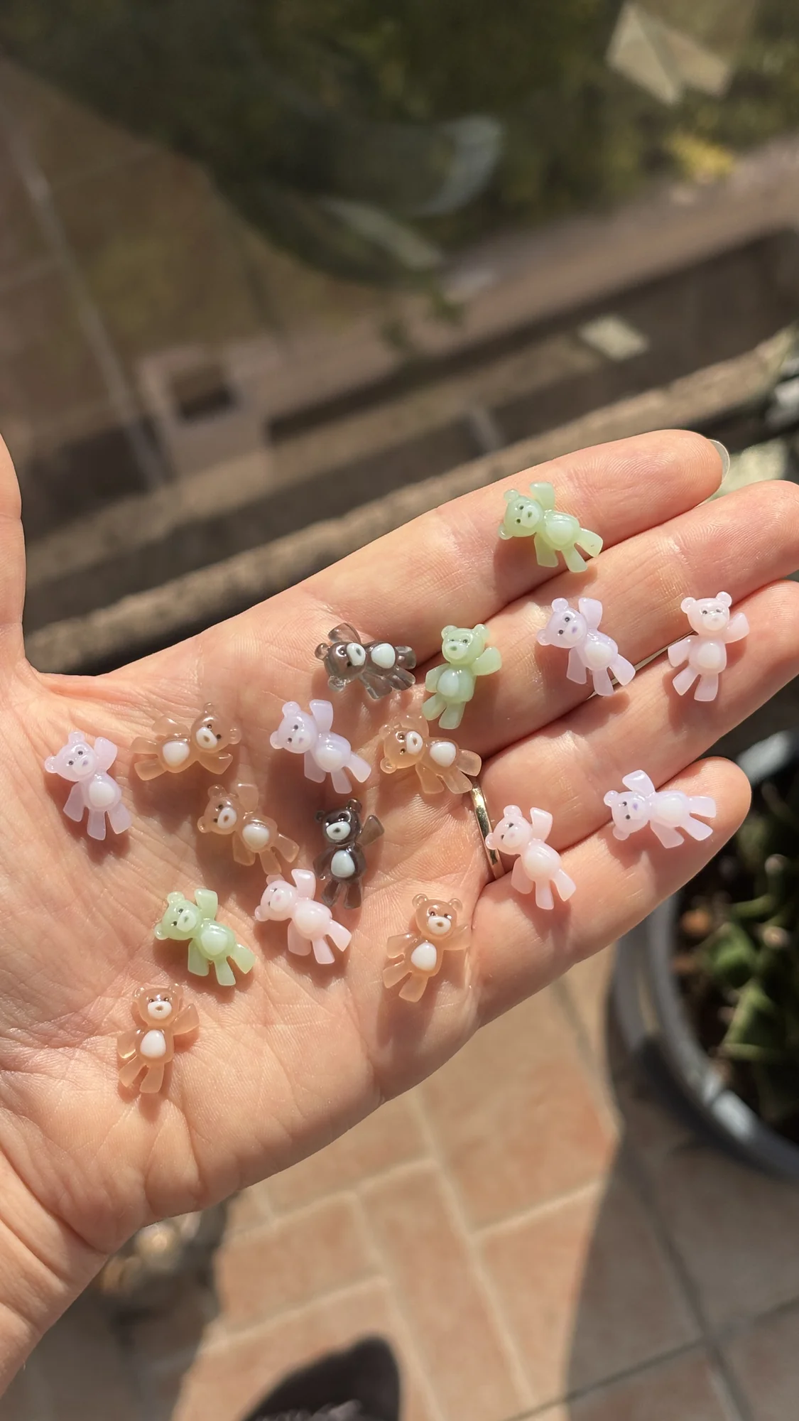 Charms oursons faits main dans le creux d'une main, en rose, lilas, brun, vert et gris
