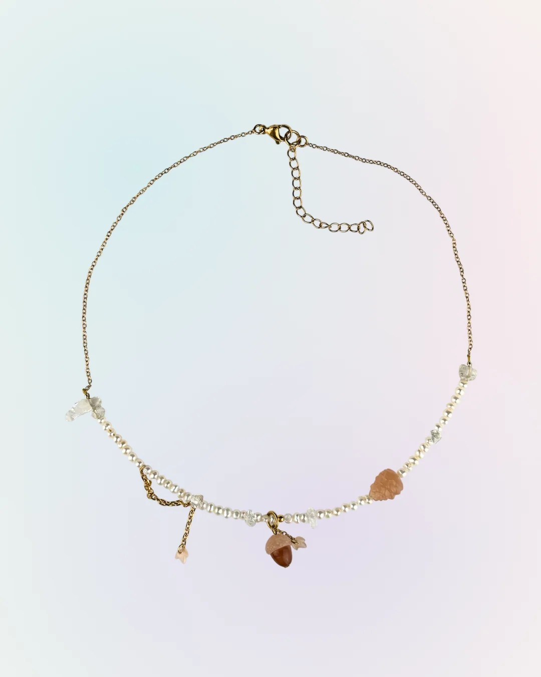Collier Forêt doré présenté à plat : chaîne fine, perles d'eau douce, charm gland et charm pomme de pin, collection Remember October Odyssée Bijoux