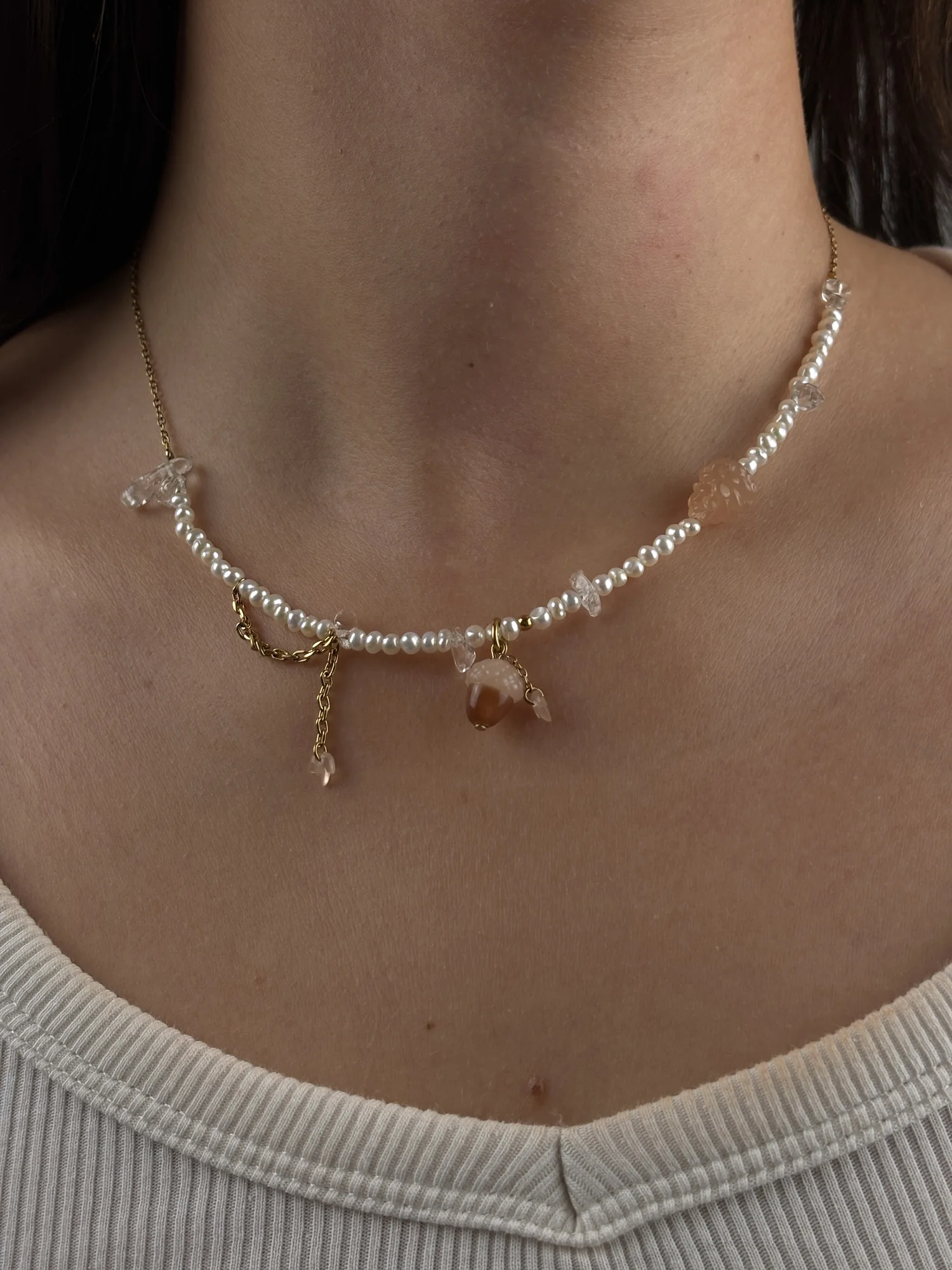 Collier Forêt doré porté sur un débardeur blanc, charm gland au centre et charm pomme de pin sur le côté