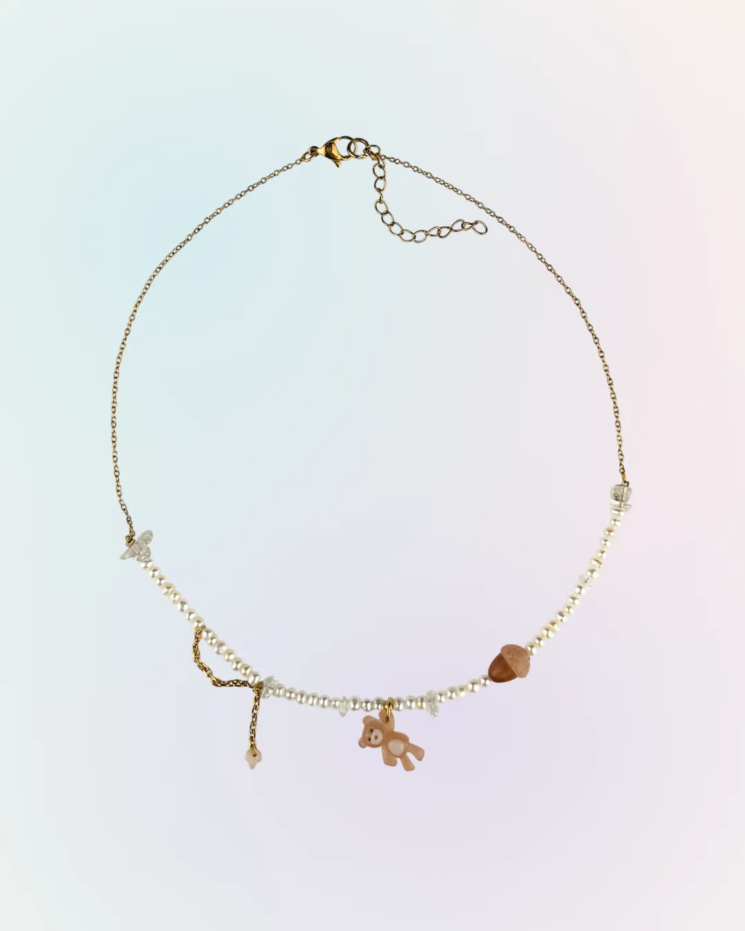 Collier Ourson Brun doré présenté à plat : chaîne fine, perles d'eau douce, charm ourson brun et charm gland, collection Remember October Odyssée Bijoux