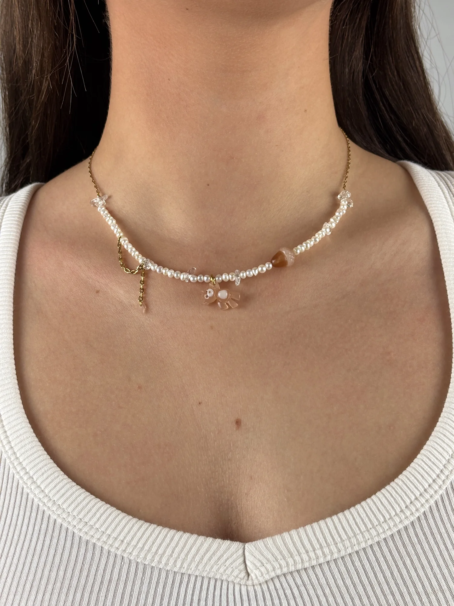 Collier Ourson Brun doré porté sur un débardeur blanc, perles d'eau douce, charm ourson brun et charm gland