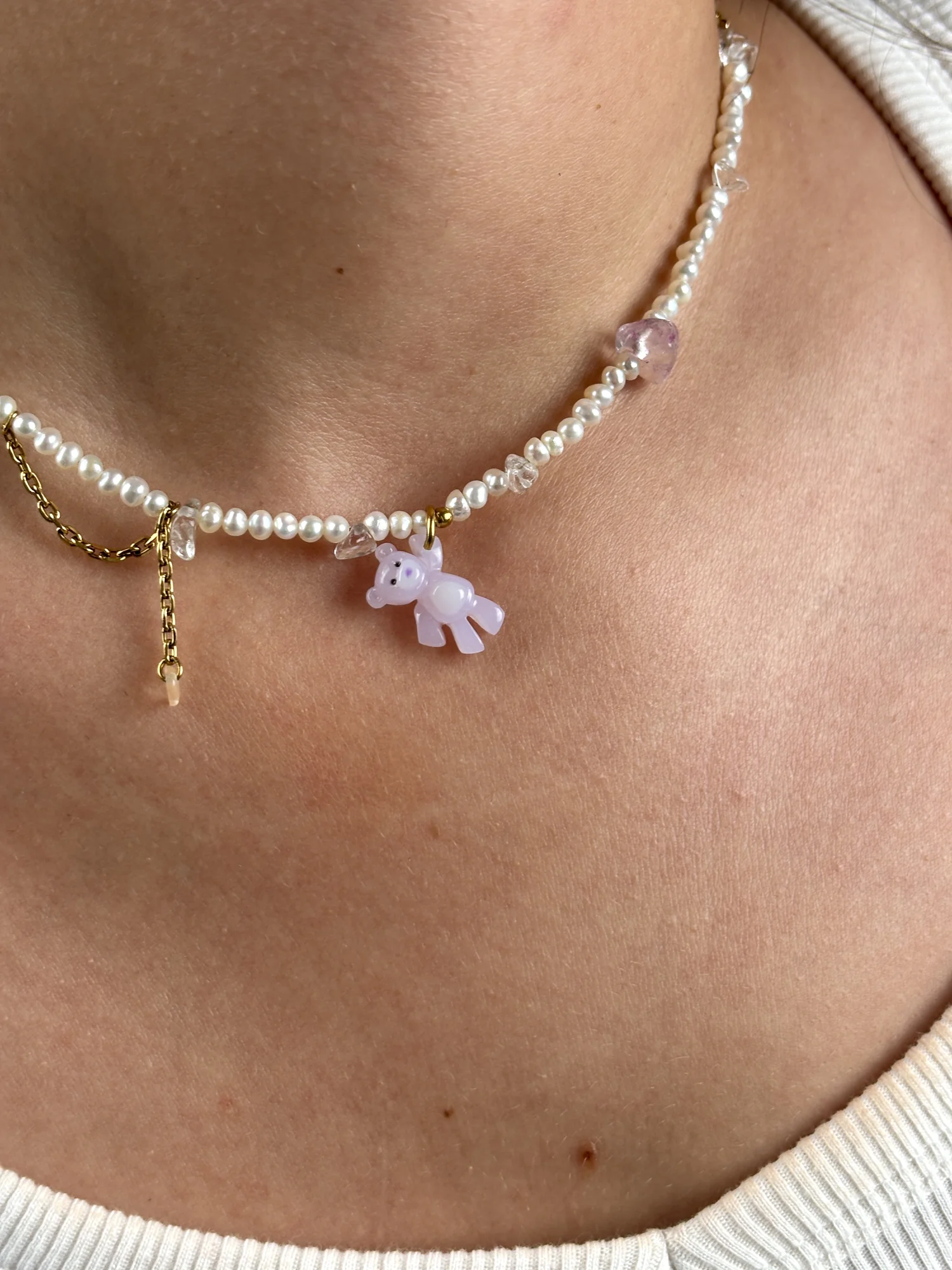 Gros plan du collier Ourson Lilas porté : charm ourson lilas, perles d'eau douce et chaîne dorée