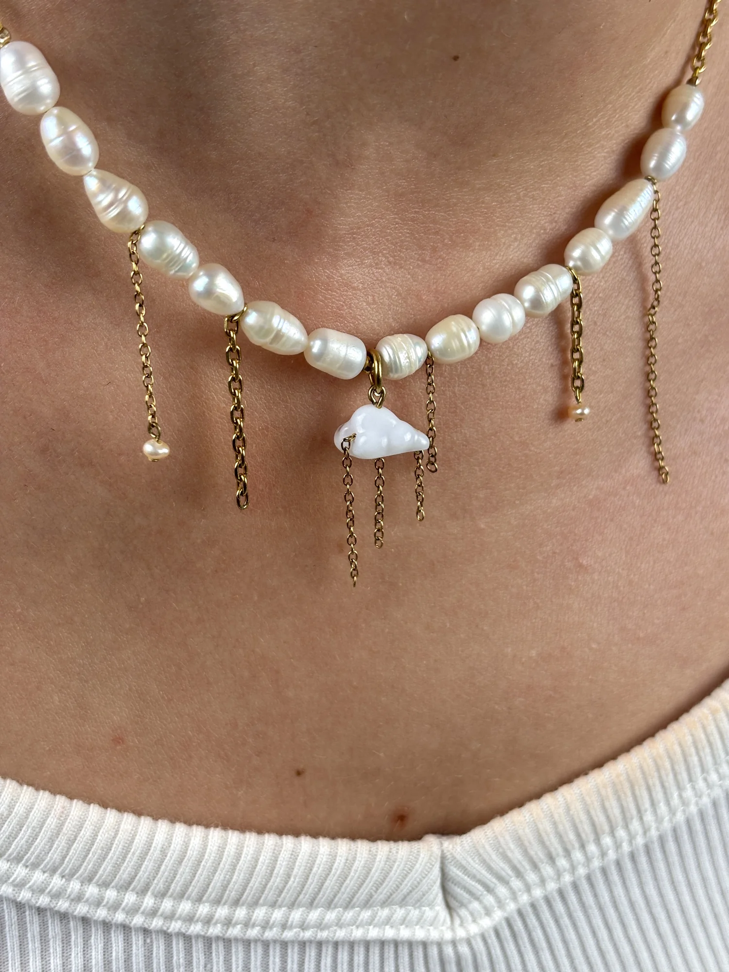 Gros plan du collier Pluie d'automne porté : charm nuage blanc, perles d'eau douce et fines chaînes dorées comme des gouttes de pluie