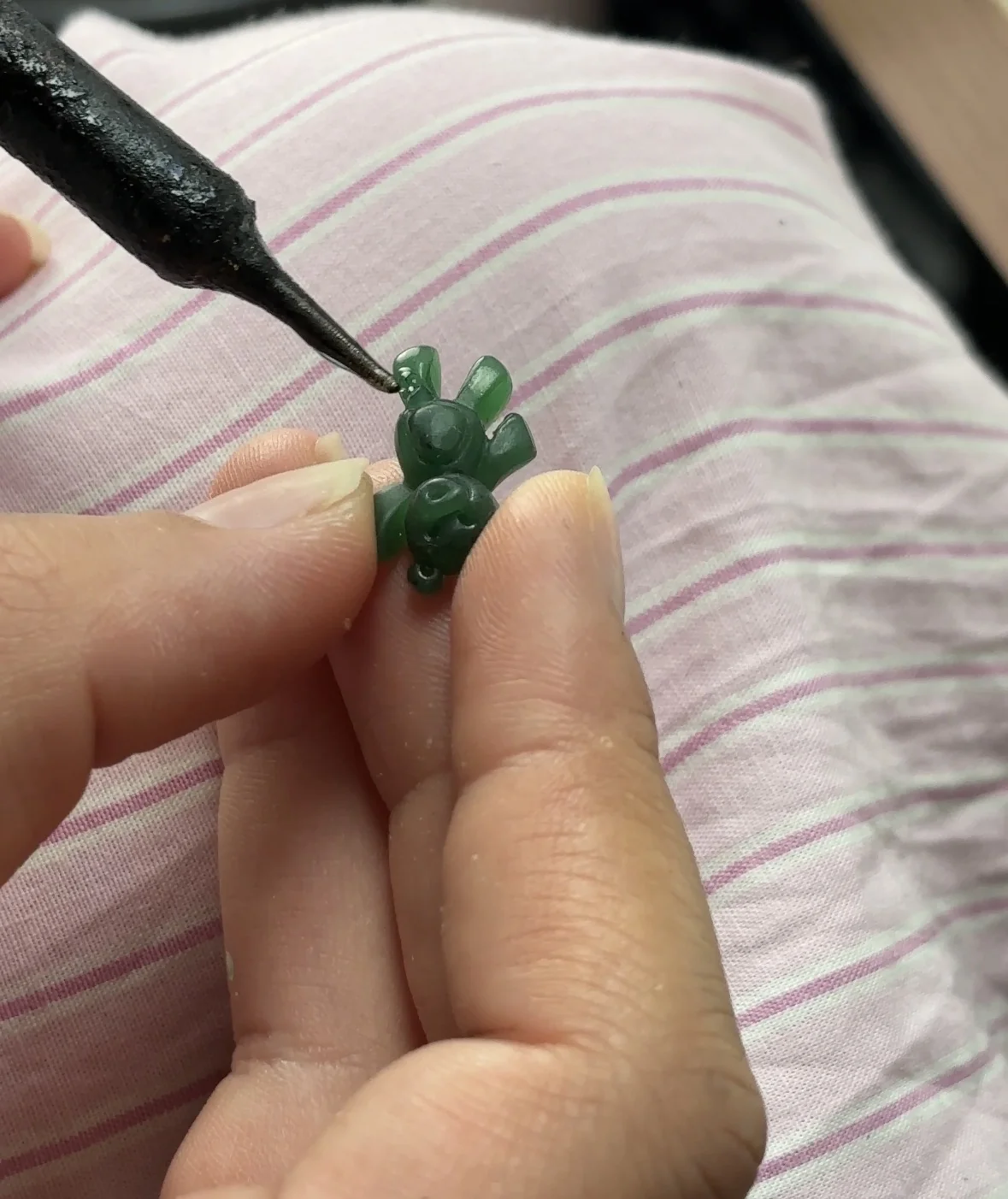Petit ourson vert sculpté à la main avec un outil de précision, étape de création du charm ourson