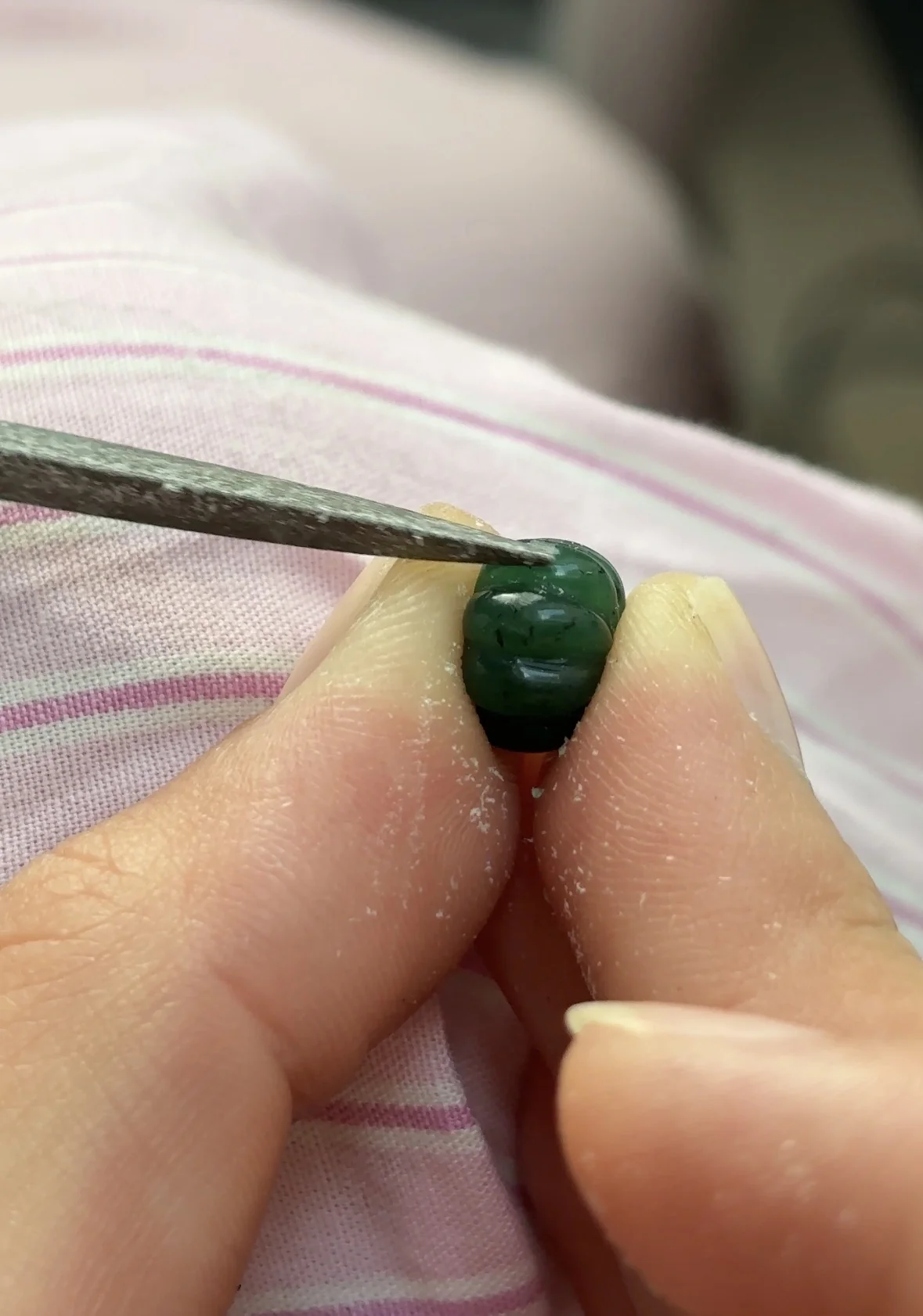 Petite pièce verte arrondie façonnée à la main avec une lime, étape de création d'un charm