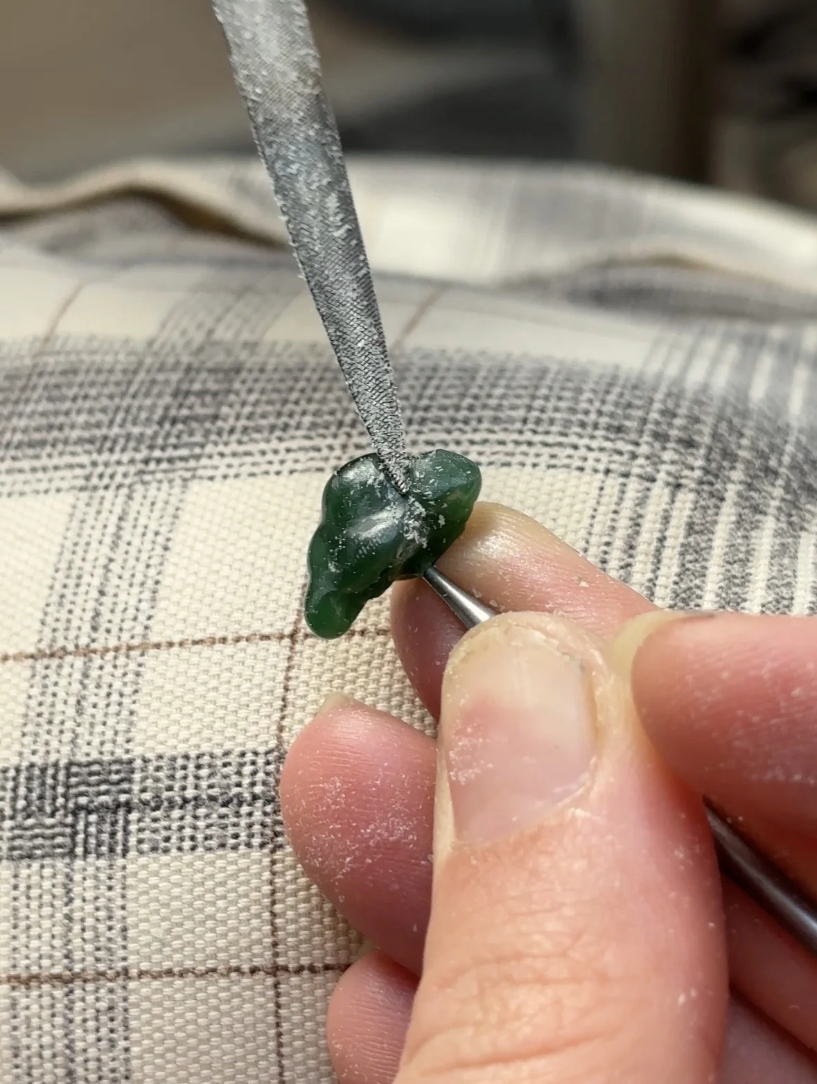 Petite pièce verte sculptée à la main avec une lime, étape de création d'un charm