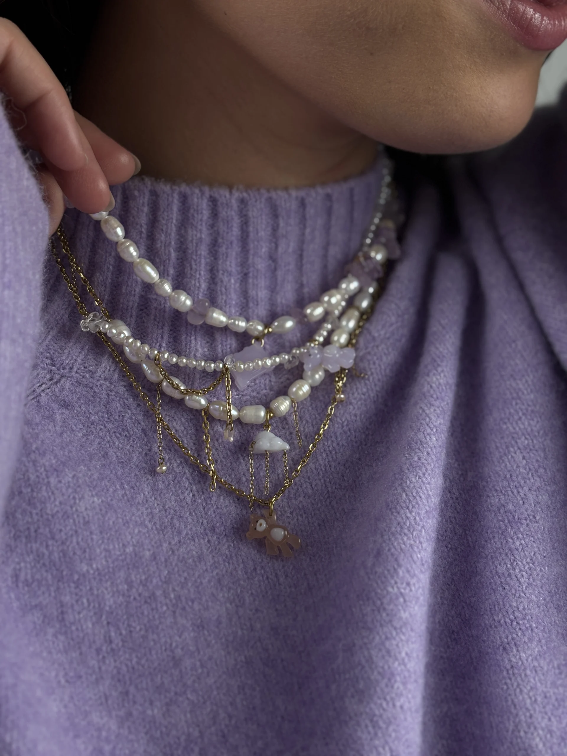 Colliers de la collection Remember October superposés, portés sur un pull lilas